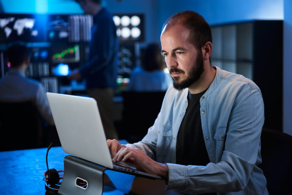 Financial Analyst Working On A Computer With Multi Monitor Workstation Stocks, Commodities And Exchange Market Charts. Businessman Works In Investment Bank Downtown Office At Night. - Moura Serviço Contábeis